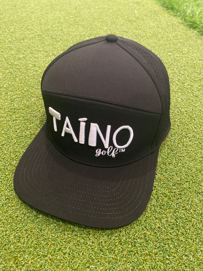 Waterproof Taino Golf hat in black, featuring the Taino Golf logo in white on the front, displayed on a putting green.