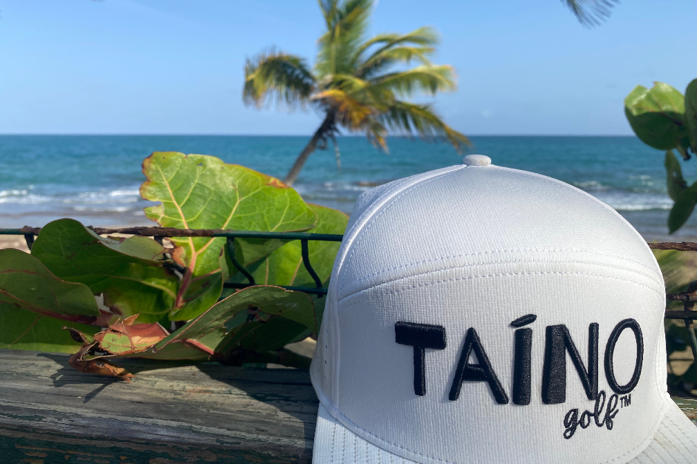 Taino Golf hat with beach and palm trees in the background.