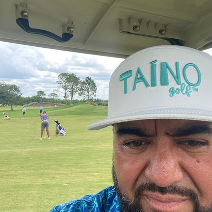 Dad watching his son play in a golf tournament while wearing a white Taino Golf hat with teal logo embroidered on the front.