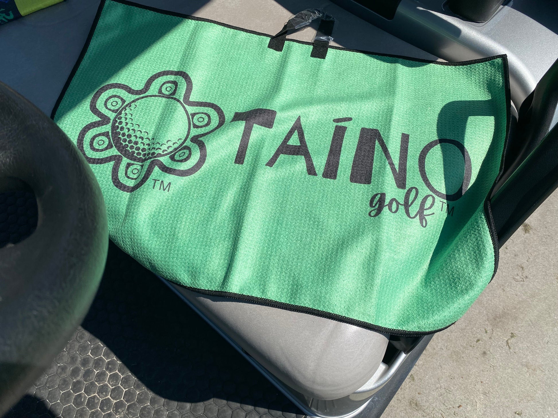 Taino Golf green double-sided microfibre waffle towel, featuring a durable, absorbent fabric for cleaning golf clubs and hands, with a native inspired design and Taino Golf branding.